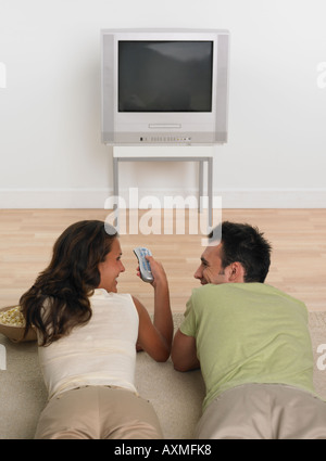 Paar Verlegung Erdgeschoss mit Popcorn vor dem Fernseher Stockfoto