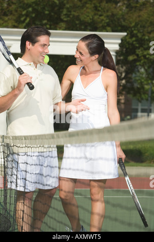 Paar sprechen auf Tennisplatz Stockfoto