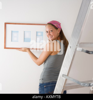 Junge Frau Bild an Wand hängen Stockfoto