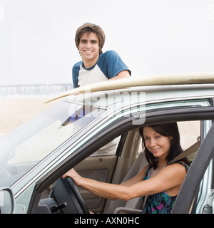 Paar und Auto mit Surfbrett an der Spitze am Strand Stockfoto