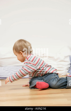 Baby Junge sitzt auf einer Etage, versucht, sich umzudrehen Stockfoto