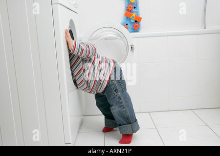 Babyjungen suchen in einer Waschmaschine Stockfoto