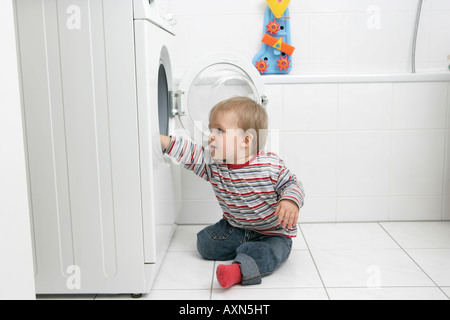 Baby Junge sitzt vor einer Waschmaschine Stockfoto