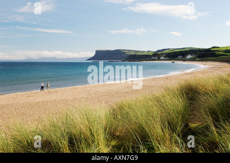 Ein Paar mittleren Alters spaziert am Ballycastle Beach, County Antrim, Nordirland. Blick auf die Landzunge von Fair Head Stockfoto