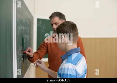 Lehrer und Teenager an Tafel schreiben Stockfoto