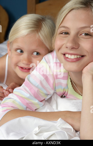 Zwei blonde Mädchen lächelnd im Bett liegend Nahaufnahme Stockfoto