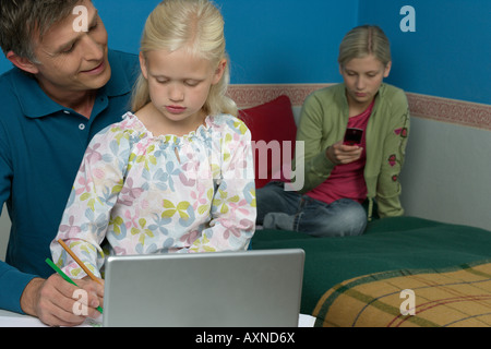 Mann sitzt hinter einem Laptop mit seiner Tochter beim Zeichnen in einem Skizzenbuch, selektiven Fokus Stockfoto