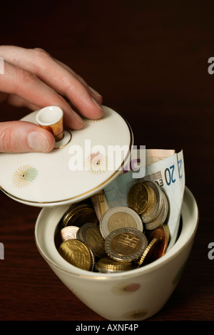 Hand, die den oberen Rand eine Zuckerdose gefüllt mit Euro-Scheine (Teil), Nahaufnahme Stockfoto