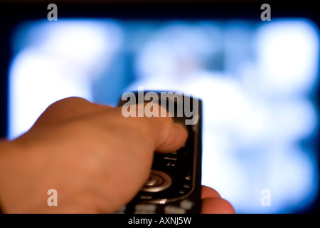 Halten Sie eine Fernbedienung, die darauf abzielen, einen TV Stockfoto