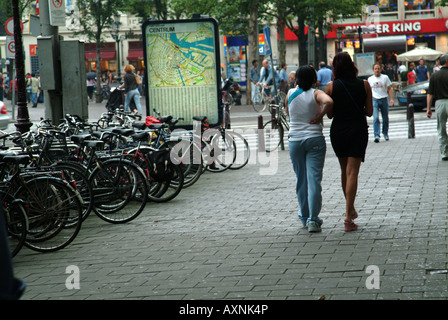 Eine Straße in Amsterdam mit Bikes oder Fahrräder eingesperrt entlang es und Straßenmusiker spielen Stockfoto