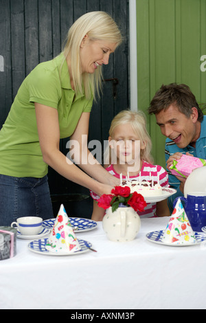 Kleine blonde Mädchen Ausblasen der Kerzen ihre Geburtstagstorte Stockfoto