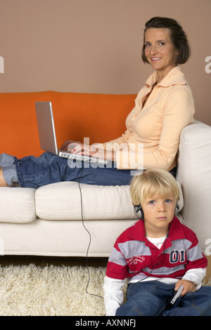 Mutter mit einem Laptop, Sohn (4-5 Jahre) anhören von Musik über Kopfhörer Stockfoto
