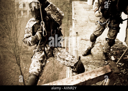 Ein Anti-Terror-Soldat ist während der Übungen in einem verwüsteten Gebäude Abseilen. Ein anderes bereitet sich auf ihm zu folgen. Stockfoto