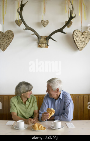 Senior paar sitzen unter einer Dekoration der Kork Herzen beim Frühstück Stockfoto
