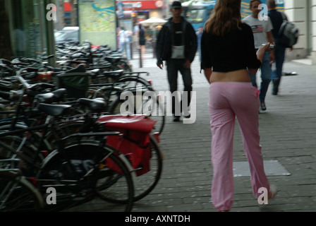 Eine Straße in Amsterdam mit Bikes oder Fahrräder eingesperrt entlang es und Straßenmusiker spielen Stockfoto