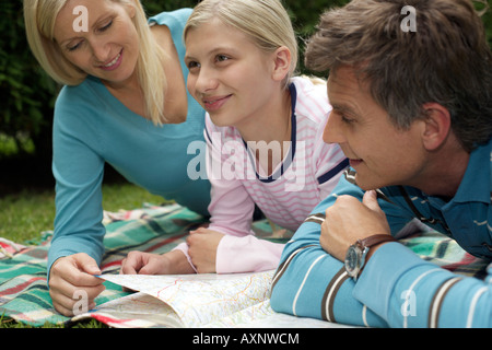 Mutter, Vater und Tochter Blick auf eine Karte beim liegen auf einer Wiese, selektiven Fokus Stockfoto