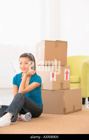 Asiatische Frau sitzt neben Umzugskartons Stockfoto