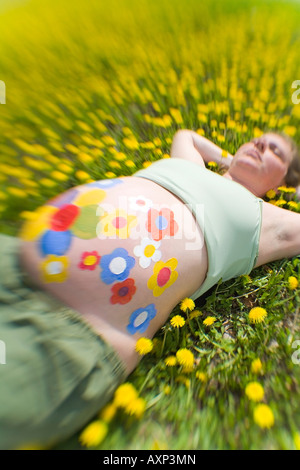 Schwangere Frau Verlegung unter Wildblumen mit Blumen gemalt auf dem Bauch USA Stockfoto