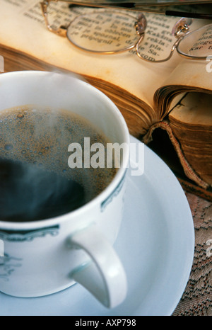 Weiße Tasse dampfenden Kaffee auf einem Tisch mit einem Buch Stockfoto