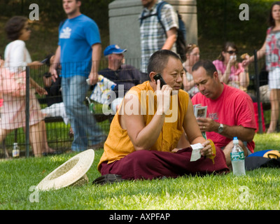 Ein junger Mann spricht auf seinem Handy, als er auf dem Rasen im Central Park in New York City USA sitzt Stockfoto