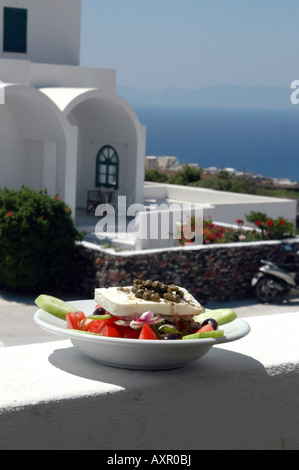 griechischer Salat mit Kykladen-Architektur im Hintergrund über Ägäis Stockfoto