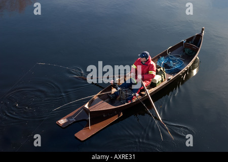 Fischer Trolling mit einem traditionellen hölzernen Ruderboot / Schiff am Fluss Oulujoki, Finnland Stockfoto