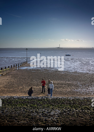 Jugendliche am Strand von Southend in Winter Docks und Fabriken in weiter Ferne sichtbar Stockfoto