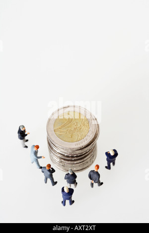 Gruppe von Geschäftsleuten Figuren um einen Stapel von Münzen Stockfoto