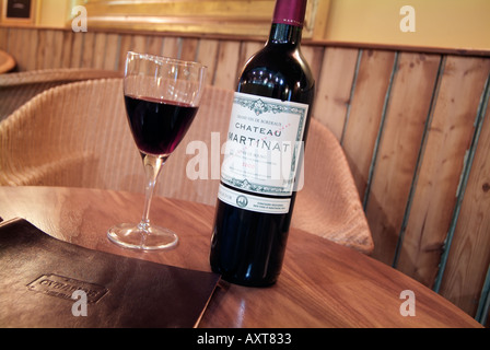 Weinstube mit Tisch mit Glas und Flasche Rotwein Stockfoto