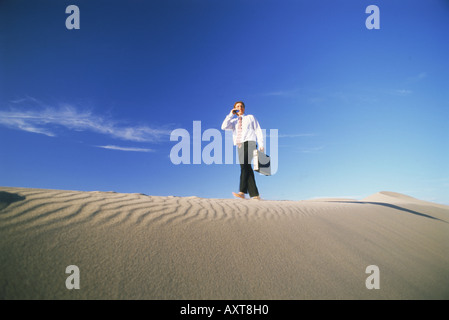 Geschäftsmann mit Aktenkoffer zu Fuß auf Sand Dune in Nevada Stockfoto