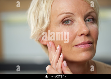 Reife Frau mit blonden Haaren berühren ihre Wange, close-up Stockfoto