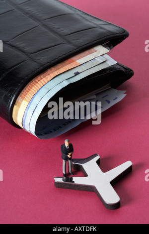 Geschäftsmann Figur auf ein Modellflugzeug, Geldbörse mit Banknoten im Hintergrund Stockfoto