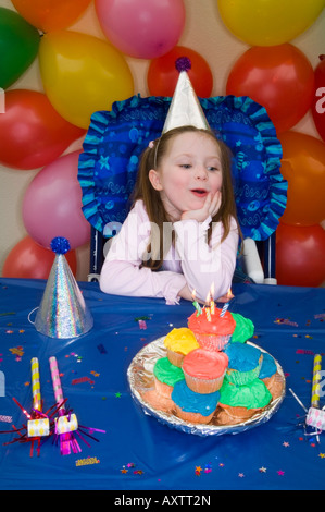 Vier Jahre altes Mädchen feiern ihren Geburtstag mit Haufen von Geburtstagstorten Cup vor ihr und Dekorationen rund um Alaska Stockfoto