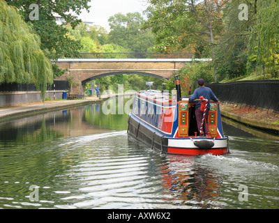 Ein Mann steuert ein Narrowboat über die Regents Canal London England Stockfoto