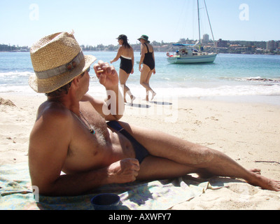 Ein Mann in Sonnenhut schaut Frauen am Reef Beach in der Sydney Harbour National Park Australien Stockfoto