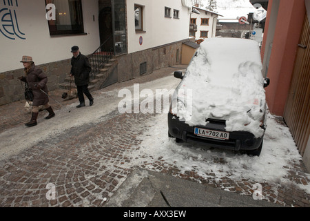 Ältere Paare, die ihren Hund durch Schnee und Eis im Ski Alpin Stadt von St. Anton, Österreich. Stockfoto