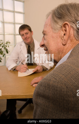 Ältere Erwachsene männliche Patienten berät sich mit jungen männlichen Arzt (gespielt von Modellen). Stockfoto