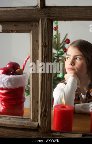 Wunschdenken Mädchen Blick aus einem Fenster, Weihnachtsbaum im Hintergrund Stockfoto