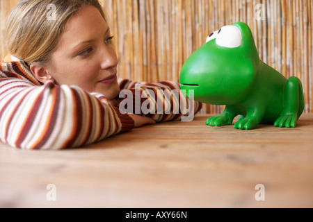Junge Frau lächelnd an einen überdimensionalen Spielzeug Frosch, selektiven Fokus Stockfoto
