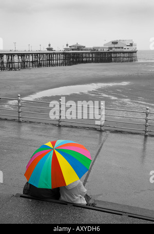 Paar Zuflucht vor dem Regen auf Blackpool Promenade mit Blick zum Nordpier Stockfoto