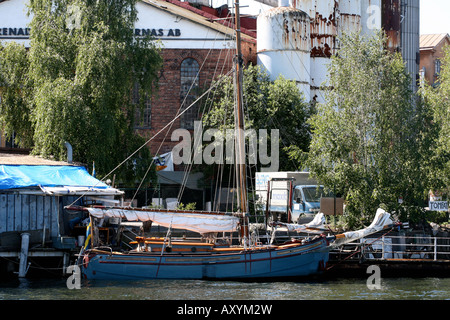 Ein Segelschiff in der Nähe von Bäumen und alten Gebäuden angedockt Stockfoto