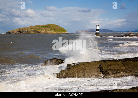 Raues windes Wetter auf dem Penmon-Leuchtturm große Wellen im Vordergrund an der wilden felsigen Küste. Penmon Point Insel Anglesey Nordwales Großbritannien Stockfoto