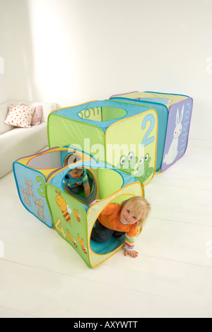 Zwei Kinder kriechen durch einen Tunnel in ein Spielhaus, gemacht von cubes Stockfoto