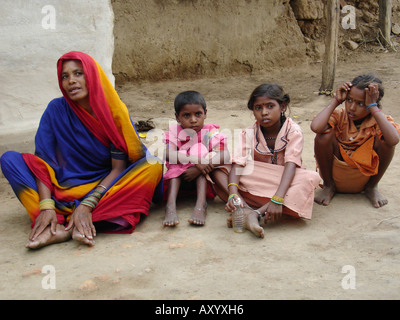 Mutter und Kinder vor einer Lehmhütte in einem sehr entlegenen und armen Dorf in Zentralindien, Indien Stockfoto