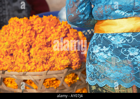 Frau In bunten Kleidern stehen neben Orange Blumen Stockfoto