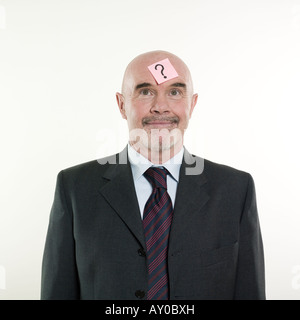 Studioportrait isoliert auf weißem Hintergrund eines Mannes Senioren mit einem Post-It mit einem Fragezeichen auf dem Kopf Stockfoto