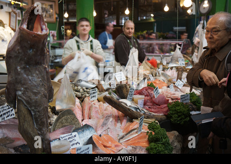 Ein Kunde, der Blick auf einen großen Fisch zum Verkauf an ein Fischhändler in Londoner Borough Market Stockfoto