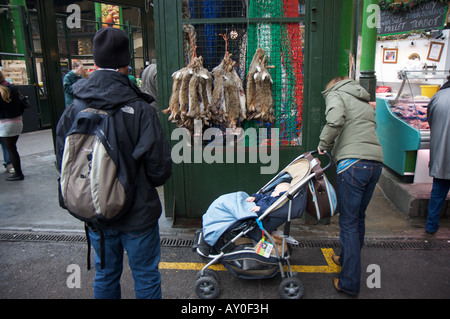 Ein Mann von Hasen zu verkaufen neben eine Frau und Ihr Baby in der Londoner Borough Market gebannt Stockfoto