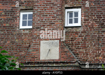Sonnenuhr zwischen zwei kleinen Fenstern der rote Backsteinhaus in Cambridgeshire Stockfoto