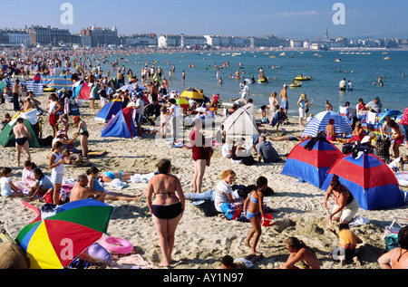 Tourists enjoying the hot soft sand in summer at Weymouth beach in Dorset county England UK Stockfoto